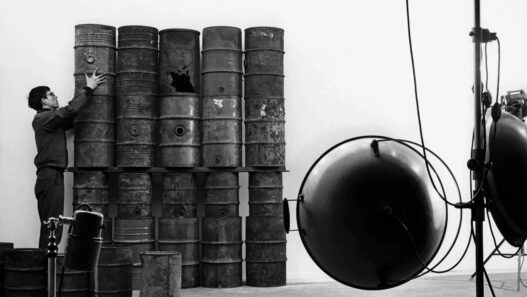 Christo during the erection of "26 Oil Barrels (1961)" in the studio of photographer Jean-Dominique Lajoux Paris, 1961