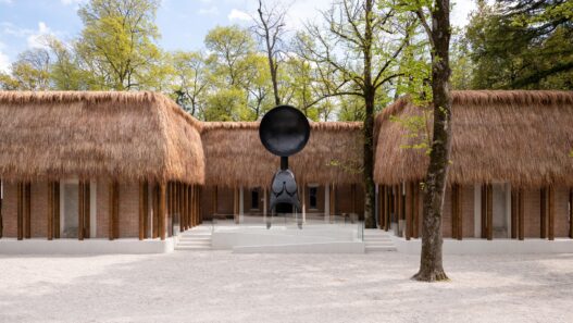 Simone Leigh: Façade, 2022. Thatch, steel, and wood, dimensions variable. Satellite, 2022. Bronze, 24 feet x 10 feet x 7 feet 7 inches (overall). Courtesy of the artist and Matthew Marks Gallery. Photo: Timothy Schenck. © Simone Leigh.