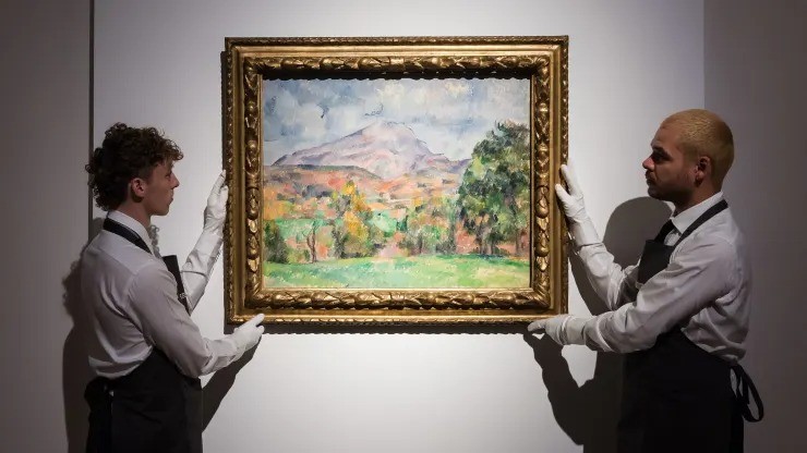 Art handlers hold a painting titled “La montagne Sainte-Victoire” by Paul Cezanne (estimate on request: in excess of $120,000,000) during a photo call to present the highlights from the estate of the philanthropist and co-founder of Microsoft, Paul G. Allen in London on Oct. 14, 2022.