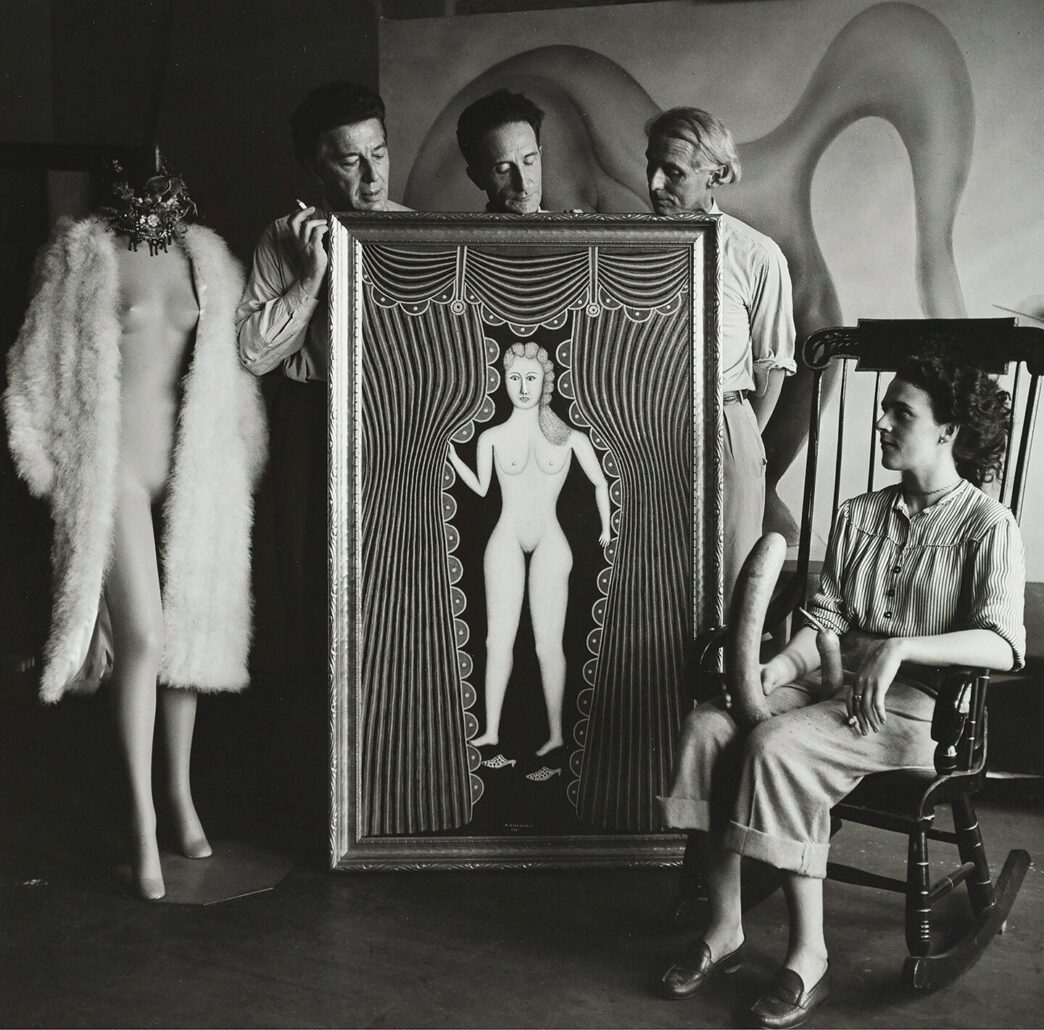 Hermann Landshoff, André Breton, Marcel Duchamp, Max Ernst [standing behind Morris Hirshfield’s Nude at the Window (Hot Night in July)], and Leonora Carrington (seated) at Peggy Guggenheim’s townhouse, Fall 1942, New York, NY. Digital print (original: gelatin silver print, 60 x 60 inches). © bpk. Digital image: bpk-Bildagentur/Münchner Stadtmuseum/Hermann Landshoff/Art Resource, New York.