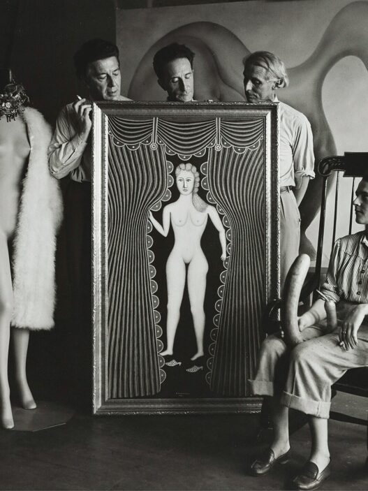 Hermann Landshoff, André Breton, Marcel Duchamp, Max Ernst [standing behind Morris Hirshfield’s Nude at the Window (Hot Night in July)], and Leonora Carrington (seated) at Peggy Guggenheim’s townhouse, Fall 1942, New York, NY. Digital print (original: gelatin silver print, 60 x 60 inches). © bpk. Digital image: bpk-Bildagentur/Münchner Stadtmuseum/Hermann Landshoff/Art Resource, New York.