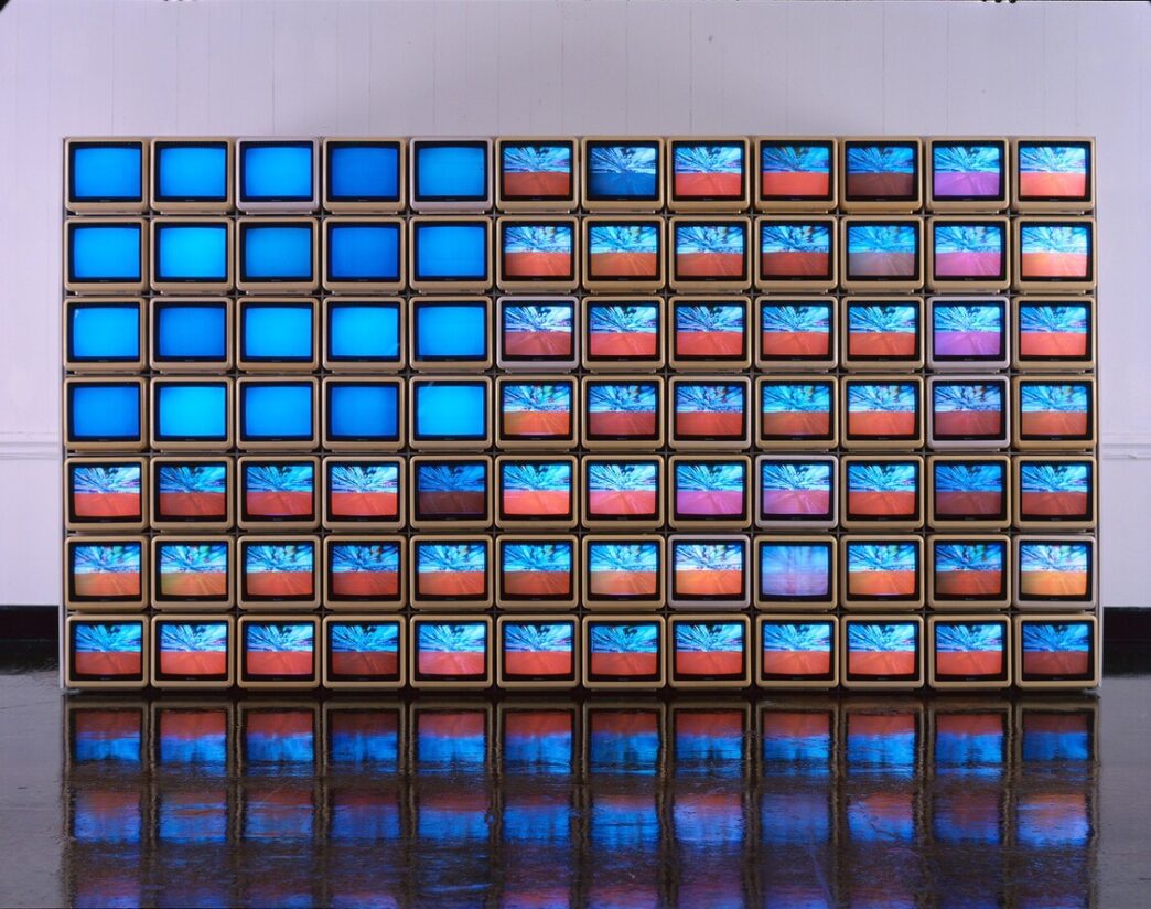 Nam June Paik, Video Flag Y, 1985. 84 ten-inch television sets, three Plexiglas cases, fans, LaserDisc players, LaserDiscs, and video tapes. 72 x 144 x 50 inches. JPMorgan Chase Art Collection. © Estate of Nam June Paik. Modern Art Museum of Fort Worth.