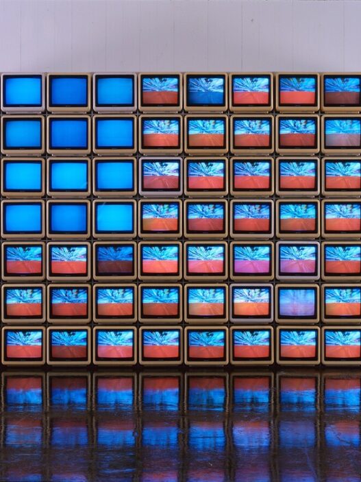 Nam June Paik, Video Flag Y, 1985. 84 ten-inch television sets, three Plexiglas cases, fans, LaserDisc players, LaserDiscs, and video tapes. 72 x 144 x 50 inches. JPMorgan Chase Art Collection. © Estate of Nam June Paik. Modern Art Museum of Fort Worth.